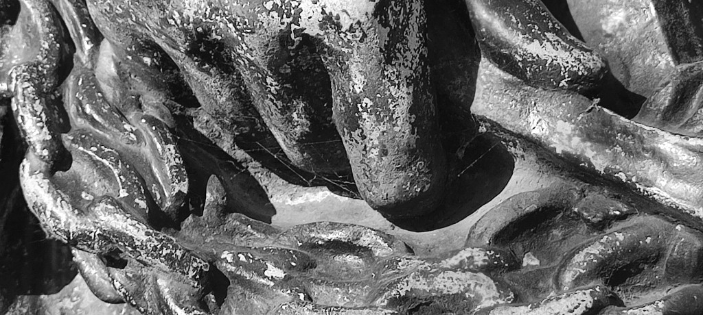 close-op black and white photo of a statue's hand wrapped about with thick chains